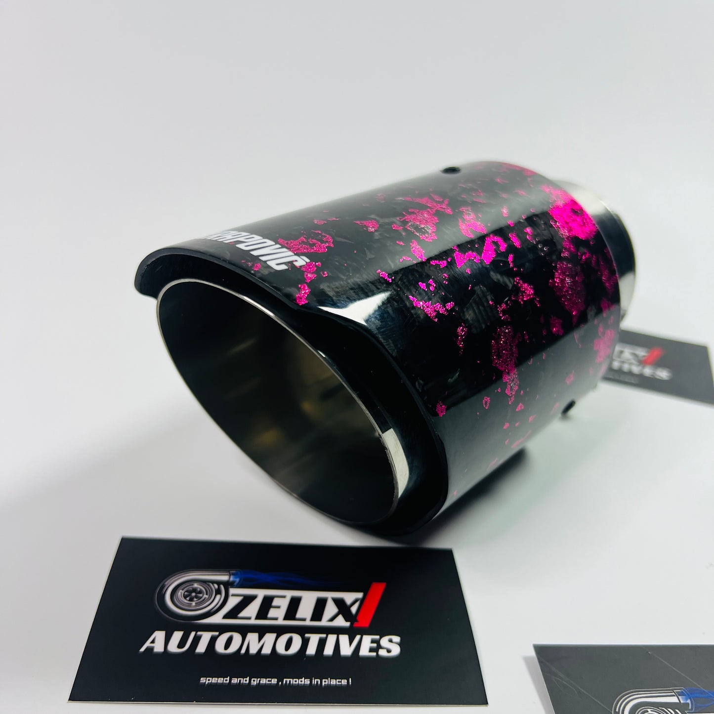 Top-down shot focusing on the oval outlet and uniform pink forged carbon weave under soft lighting.