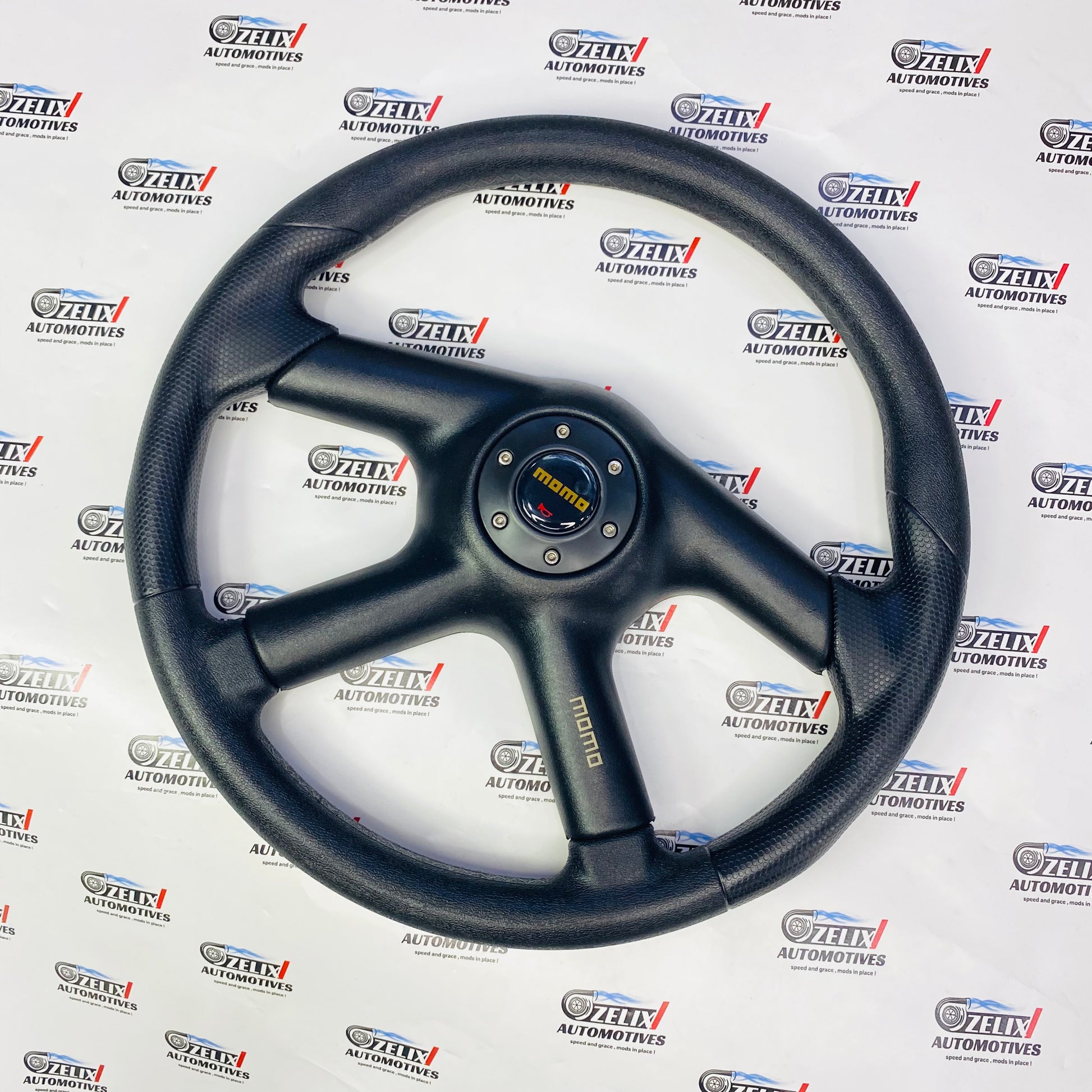 MOMO 4-Spoke Racing Steering Wheel in black leather with sport grip design