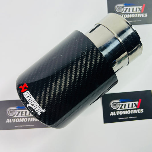Gloss carbon round single exhaust tip shown from the front, with stainless-steel inlet visible