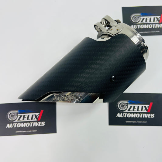 Matte carbon slant-cut exhaust tip shown from the front, highlighting the angled outlet and stainless steel clamp