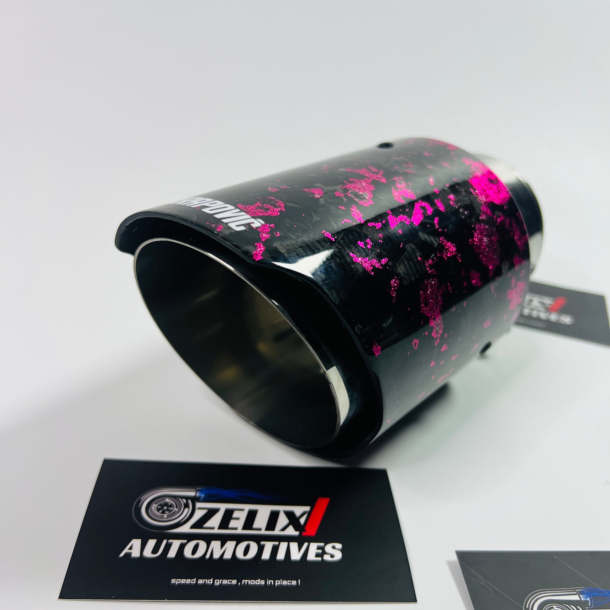 Top-down shot focusing on the oval outlet and uniform pink forged carbon weave under soft lighting.